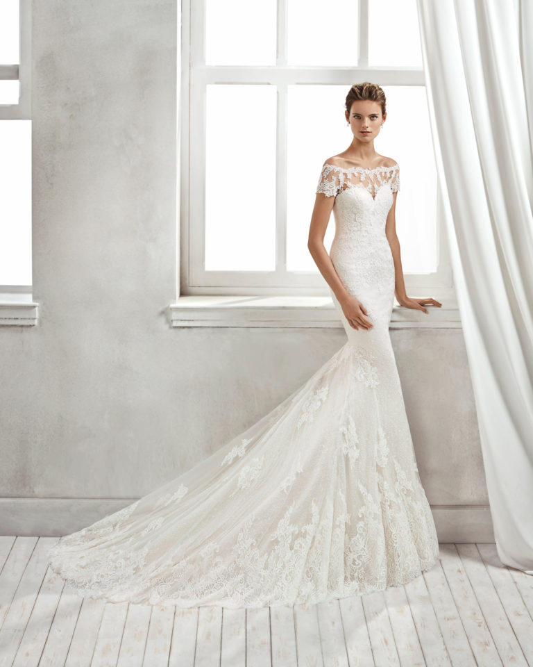 Mermaid-style lace wedding dress with off-the-shoulder neckline and lace appliqués, in nude and natural.