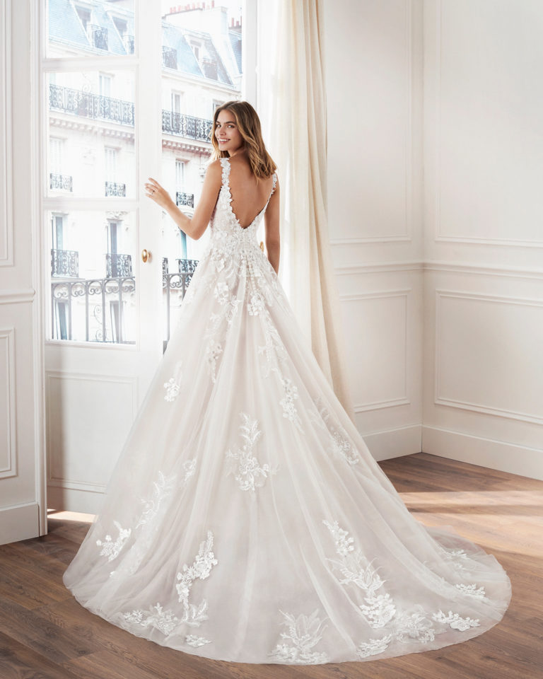 Lace princess-style wedding dress. Deep-plunge sweetheart neckline, straps, and skirt with beaded lace appliqués. Available in natural/nude and natural. 2019  Collection.