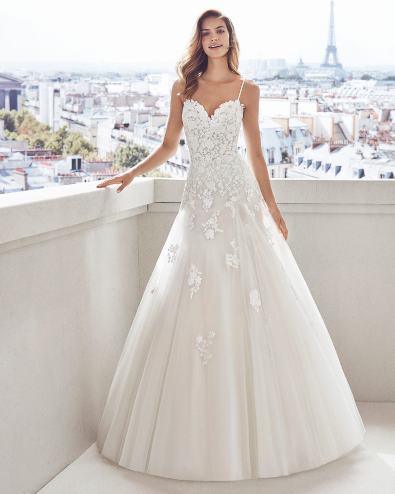 Lace and tulle princess-style wedding dress. Semi-sweetheart neckline, beaded straps and skirt and bodice with lace     appliqués. Available in natural/nude and natural. 2019  Collection.
