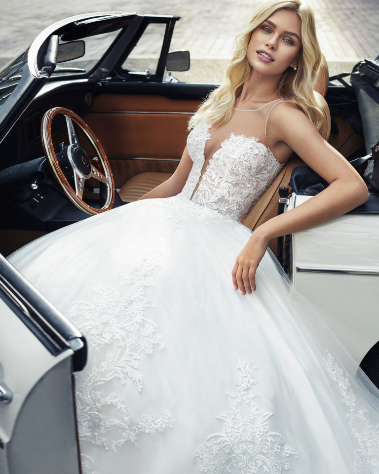 Vestido de novia estilo princesa en tul y encaje. Escote en V profundo y encaje con pedrería en sisa y escote.Disponib le en color natural. Colección 2019.