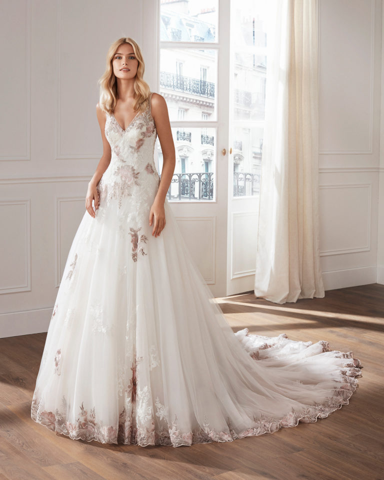 Lace and tulle princess-style wedding dress. V-neckline and skirt and bodice with beaded lace appliqués. Available in natural/pink and natural. 2019  Collection.