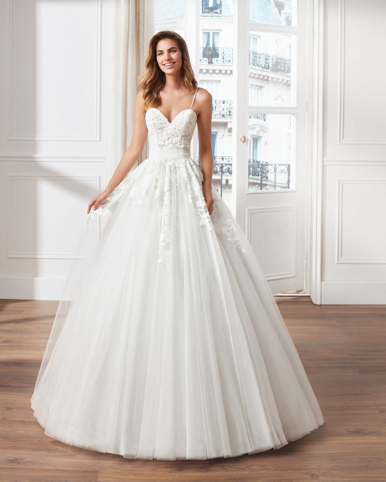 Vestido de novia estilo princesa en tul. Escote corazón, ti rantes de pedrería y aplicaciones de encaje en cuerpo y     falda. Disponible en color natural. Colección  2019.
