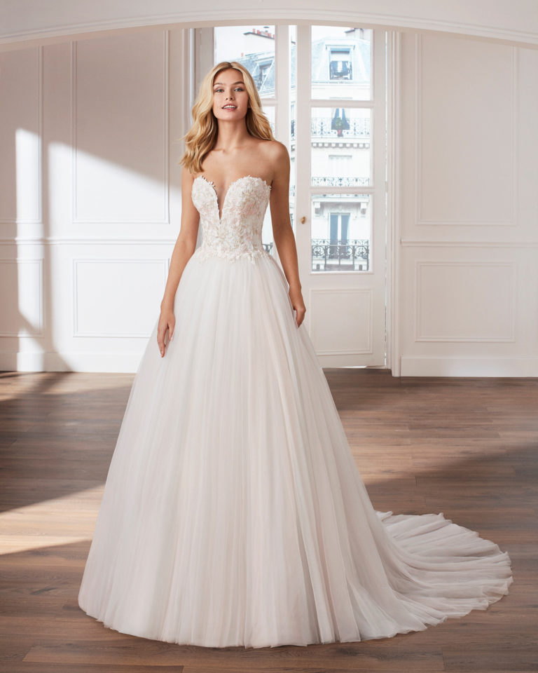 Lace and tulle princess-style wedding dress. Deep-plunge V-neckline and embroidered lace bodice. Available in pink and natural. 2019  Collection.