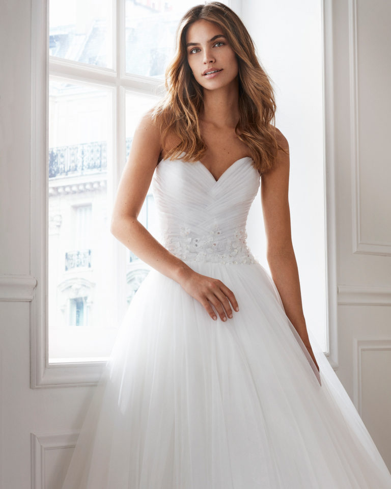 Vestido de novia estilo princesa en tul. Escote corazón y detalles de pedrería en cintura. Disponible en color natural. Colección  2019.