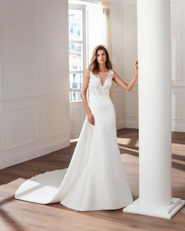 Classic-style brocade wedding dress Illusion neckline, lace bodice and removable train. Available in natural. 2019  Collection.