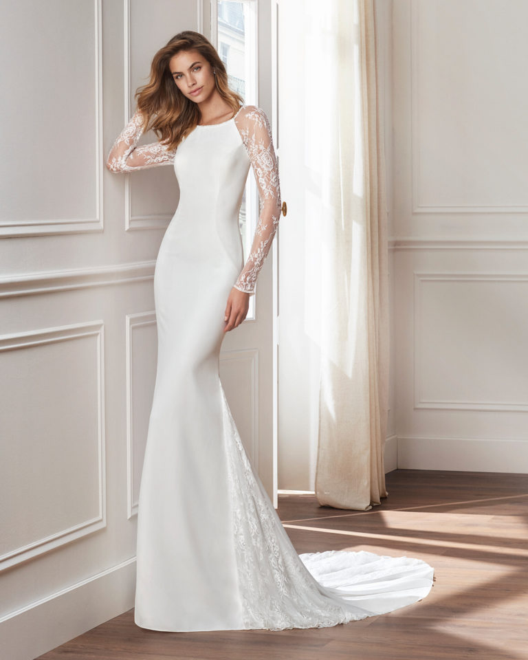 Vestido de novia corte recto en crepe. Manga larga de encaje con pedrería y encaje incrustado en la falda. Disponible en color natural. Colección  2019.