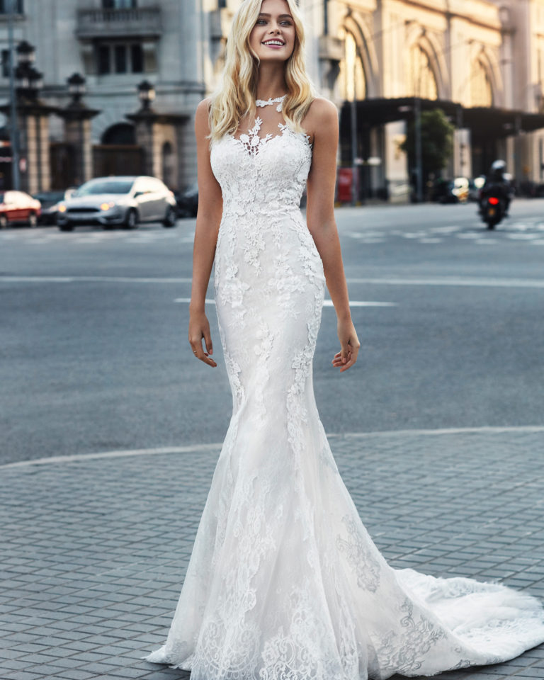 Mermaid-style wedding dress in beaded lace. V-neckline and appliquéd skirt. Available in natural and natural/nude. 2019  Collection.