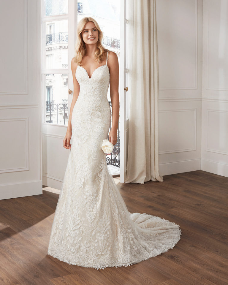 Vestido de novia corte sirena de encaje. Escote en V y falda de aplicaciones, con tirantes de pedrería. Disponible en   color natural y natural/cham                                pagne. Colección  2019.