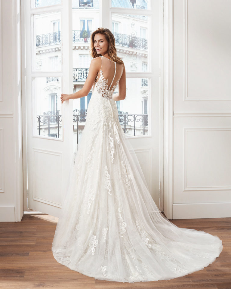 Vestido de novia corte recto de encaje. Escote en V y aplicaciones en falda. Disponible en color marfil y natural. Colección  2019.