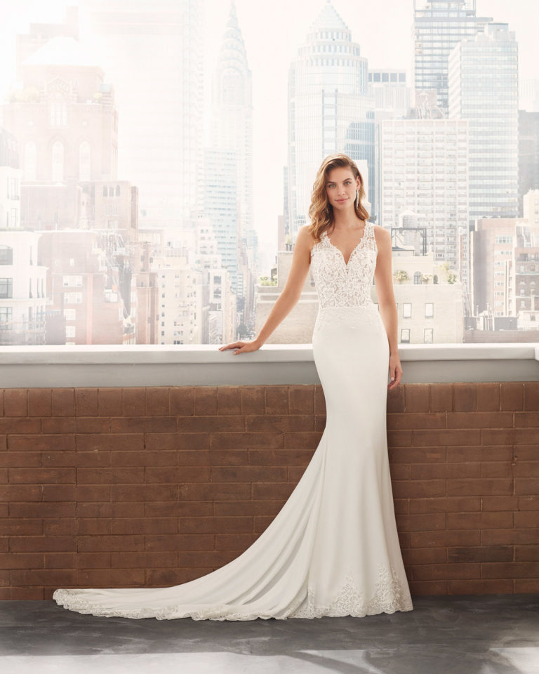 Sheath-style wedding dress in stretch crepe with lace body-shaping lining, beading at the neckline and armholes, and illusion back. 2020 Collection.