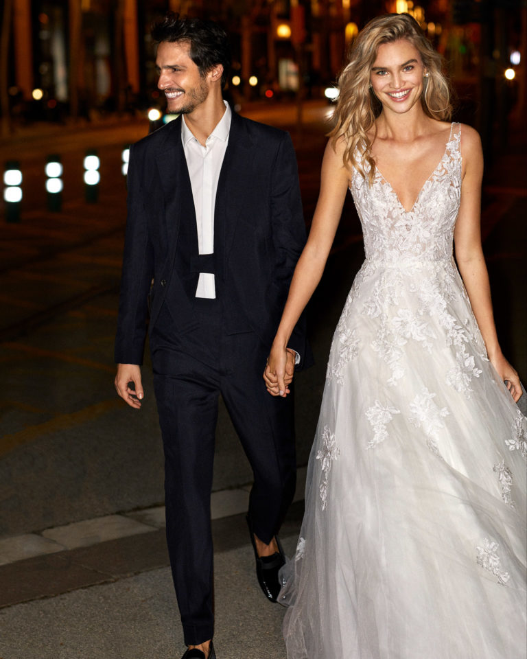 Vestido de novia de estilo romántico de encaje y tul con escote y sisa pedrería con escote y espalda en V y falda volumen. Colección 2020.