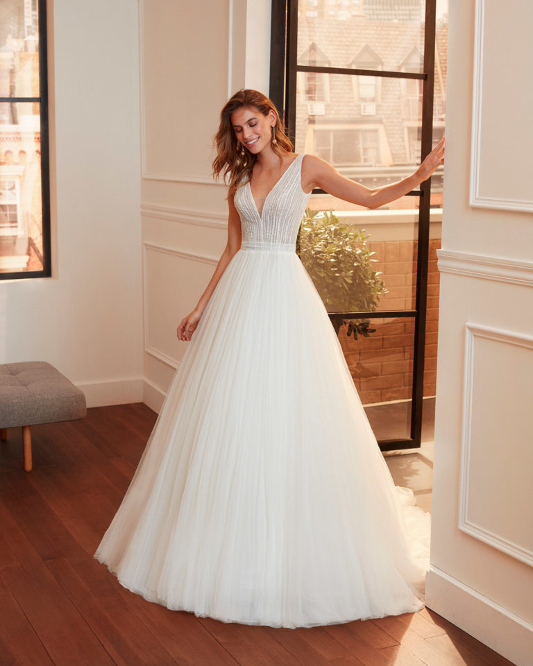Romantic embroidered tulle wedding dress with beading, deep-plunge neckline, V-back and full skirt. 2020 Collection.