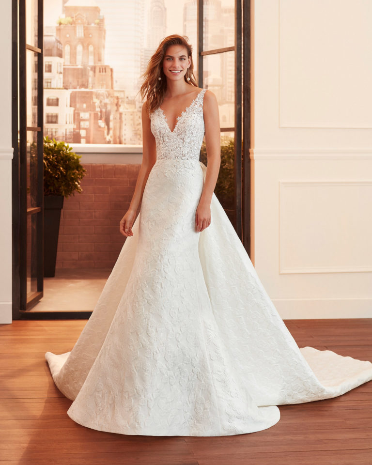 Sheath-style wedding dress and train in brocade and lace with beading, V-neckline and back with sheer inserts. 2020 Collection.