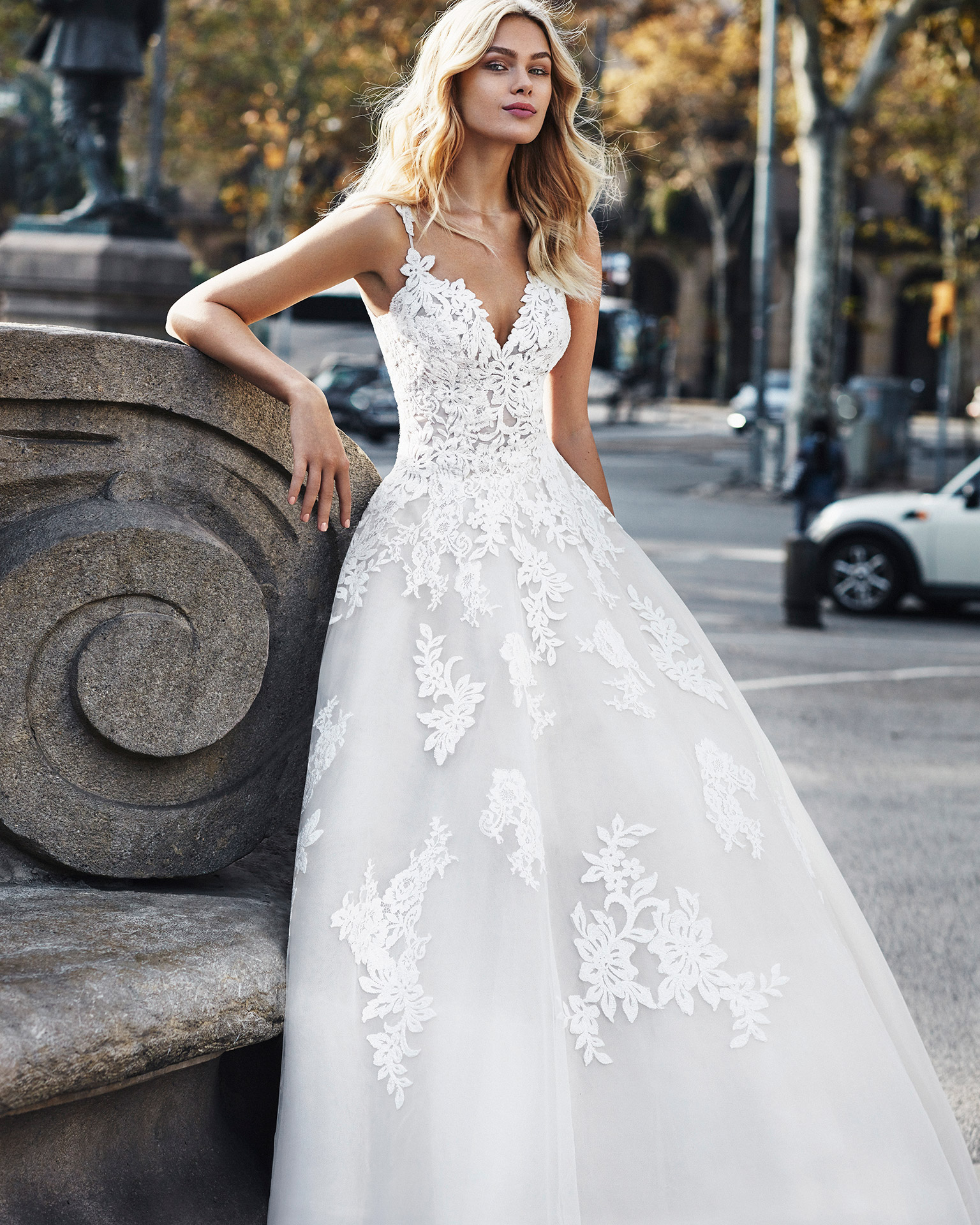 Lace princess-style wedding dress. Deep-plunge sweetheart neckline, straps, and skirt with beaded lace appliqués. Available in natural/nude and natural. 2020  Collection.