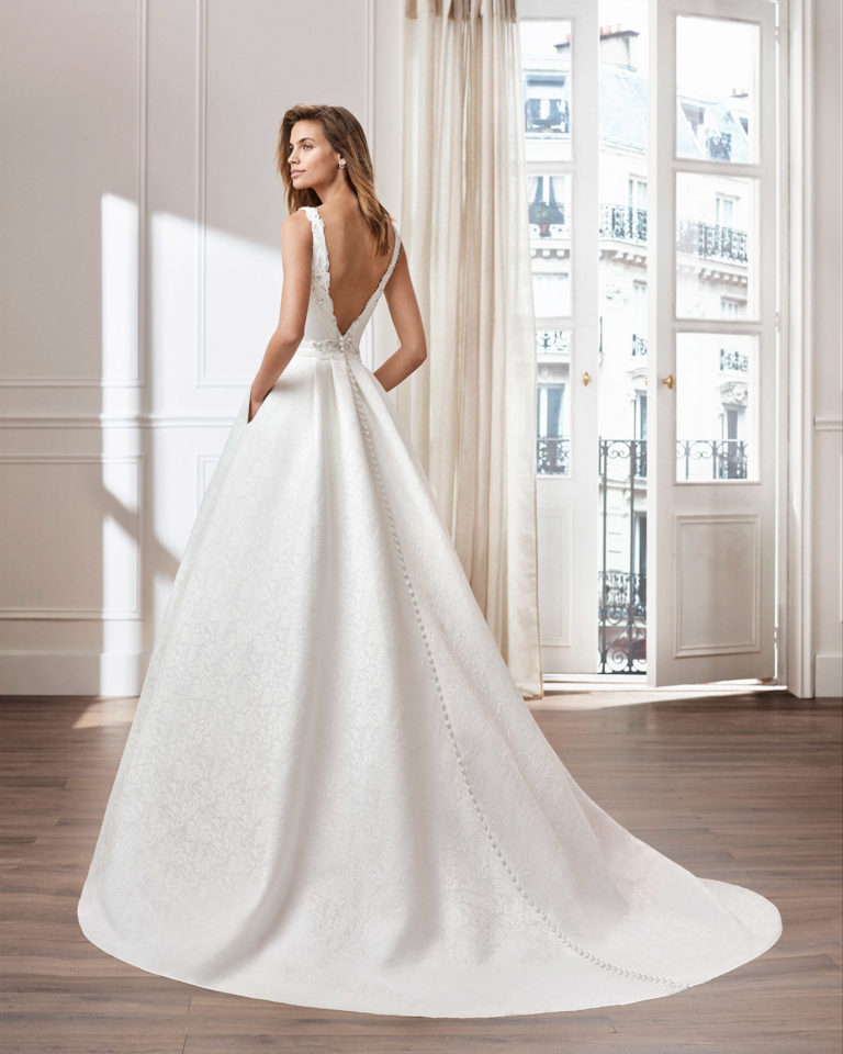 Classic A-line brocade wedding dress. Bateau neckline and jewelled back. Available in natural. 2020  Collection.