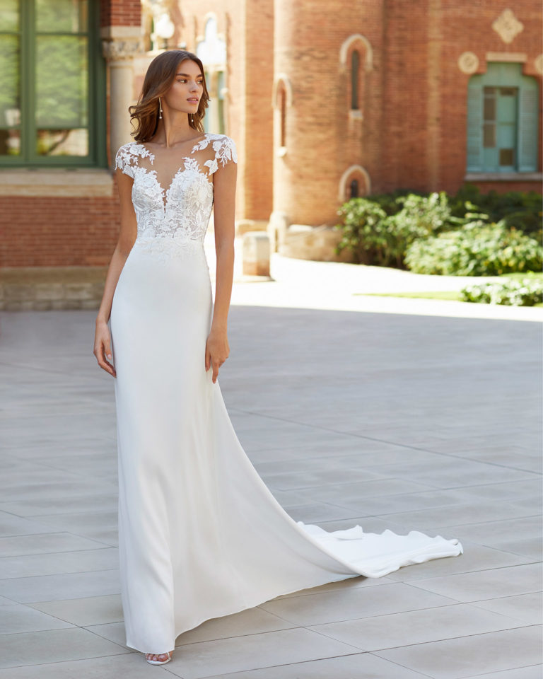 Sheath-style wedding dress in stretch crepe and lace. Deep-plunge neckline with yoke, appliqués on sleeves and open back. 2021  Collection.
