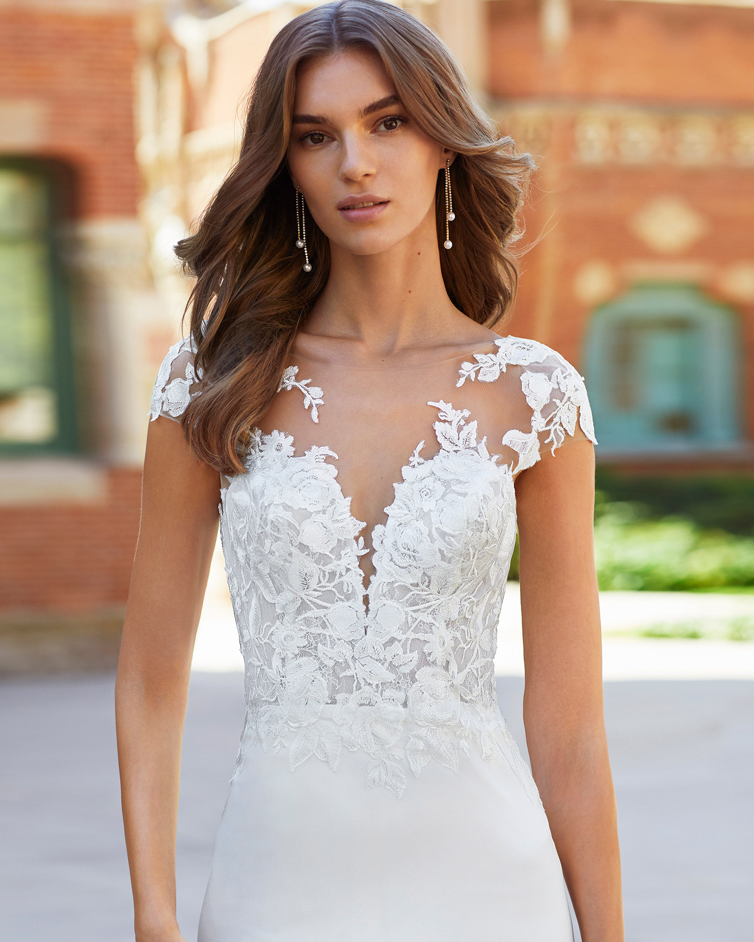 Sheath-style wedding dress in stretch crepe and lace. Deep-plunge neckline with yoke, appliqués on sleeves and open back. 2021  Collection.