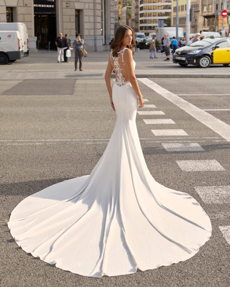 Mermaid-style wedding dress in stretch crepe and beaded lace. V-neckline and sheer back with appliqués. 2021 Collection.