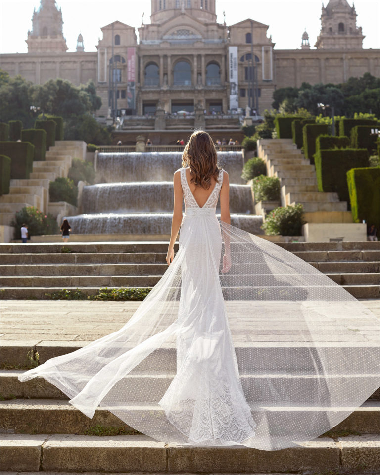 Mermaid-style wedding dress and train in lace, with dot tulle train. Deep-plunge neckline and V-back. 2021 Collection.