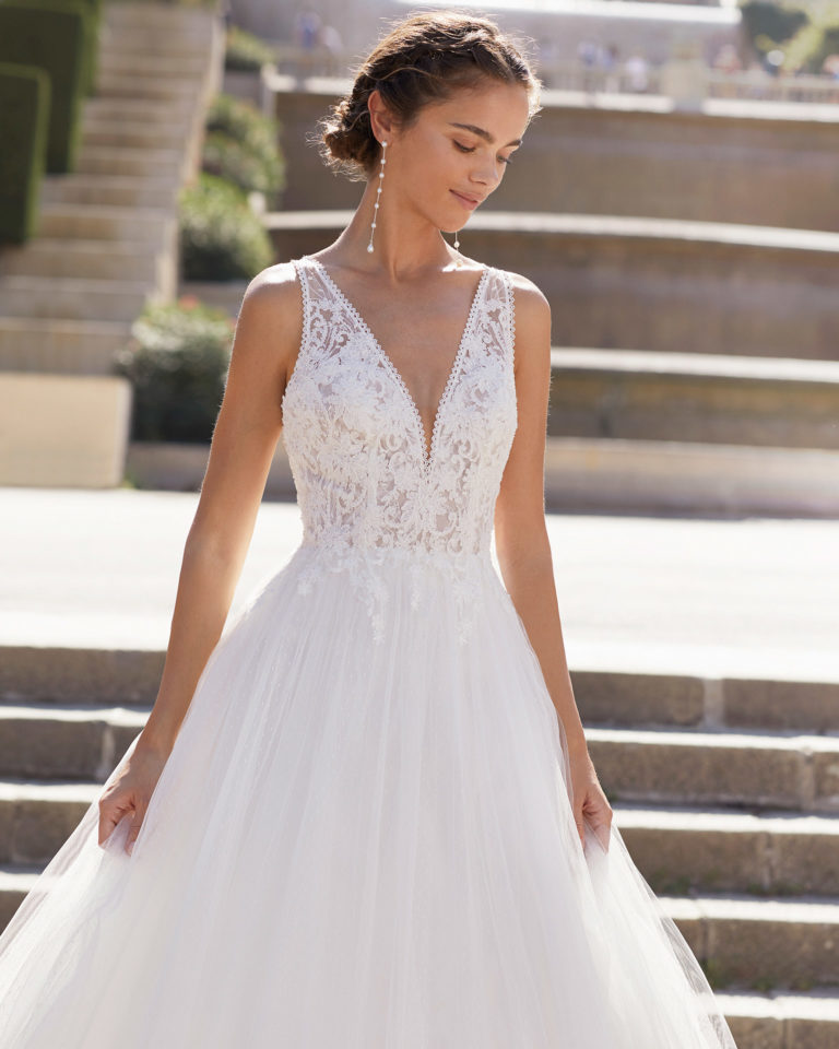 Romantic-style wedding dress in dot tulle and beaded lace. V-neckline and low back with crossover shoulder straps. 2021  Collection.