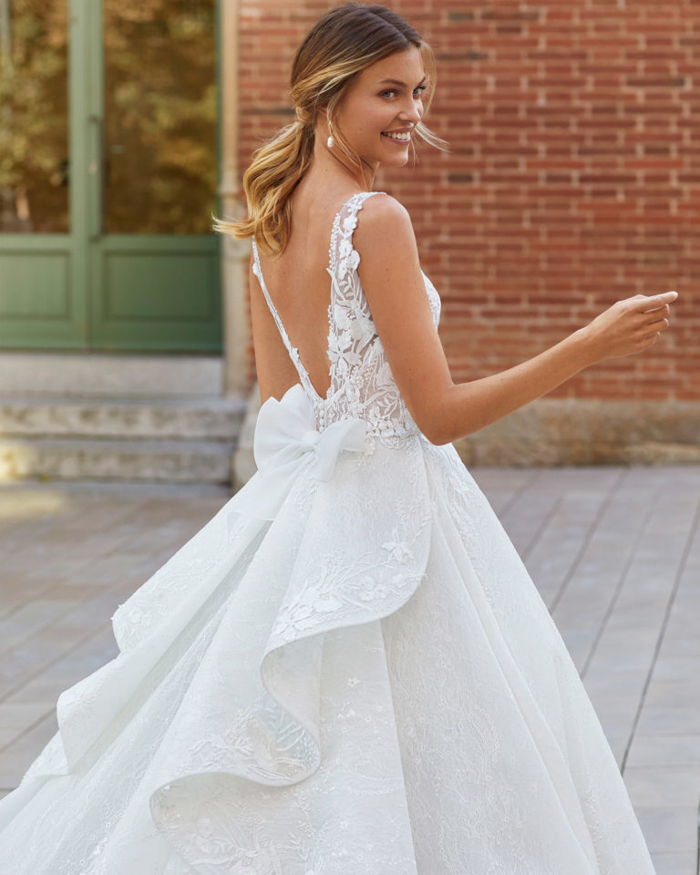 Princess-style beaded lace wedding dress. V-neckline and low back with bow. 2021 Collection.