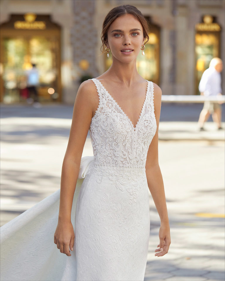 Classic-style wedding dress and train in brocade with beaded lace on waist. With V-neckline, V-back and bow on train. 2021 Collection.