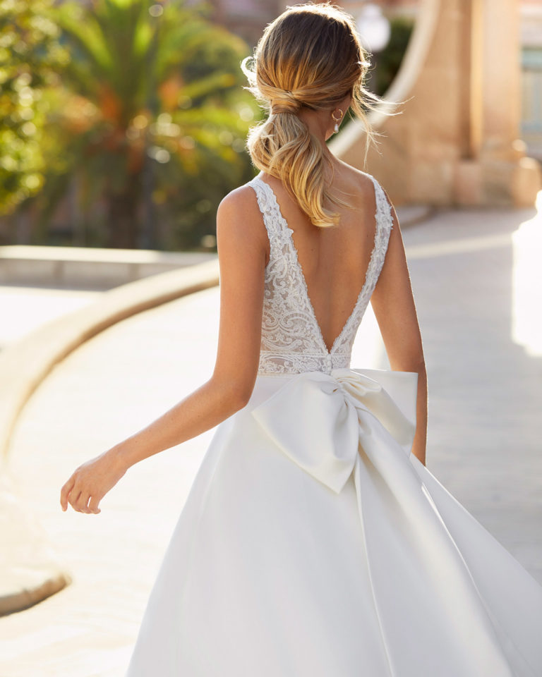 Classic-style wedding dress in satin and beaded lace. V-neckline, V-back and bow on back. 2021 Collection.
