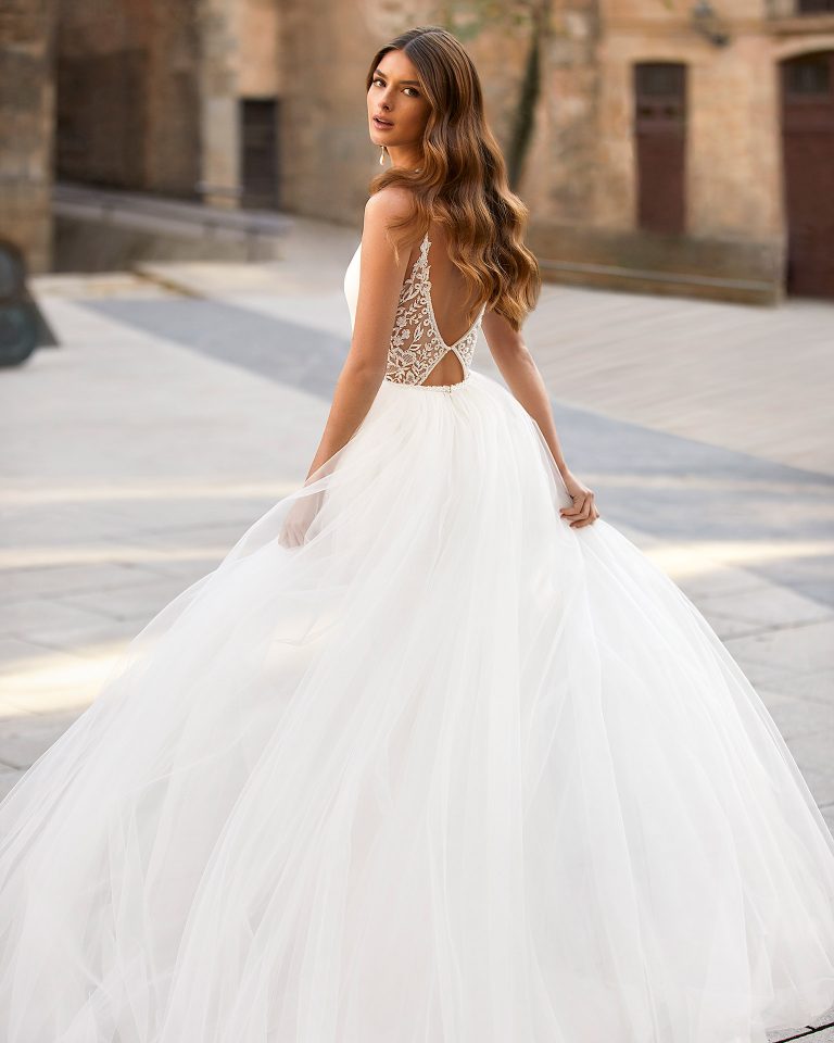 Two-piece sheath-style wedding dress made of stretch crepe, including a tulle overskirt; with a deep-plunge neckline and a lace and beadwork back. Dreamy Luna Novias outfit made of stretch crepe combined with beadwork lace and tulle. LUNA_NOVIAS.