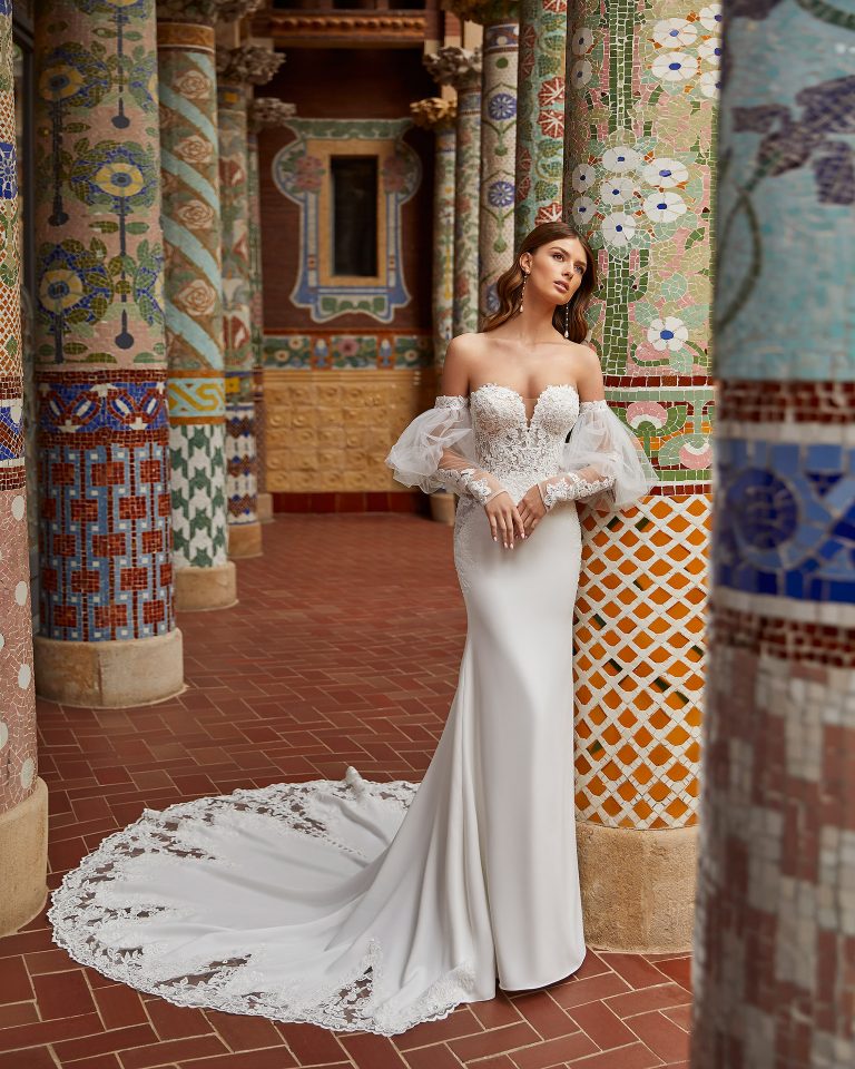 Romantic sheath-style wedding dress, made of stretch crepe, featuring a full buttoned skirt; with a push-up corset structure, a button-up lace back, and voluminous sleeves. Unique Luna Novias outfit made of stretch crepe combined with beadwork lace. LUNA_NOVIAS.