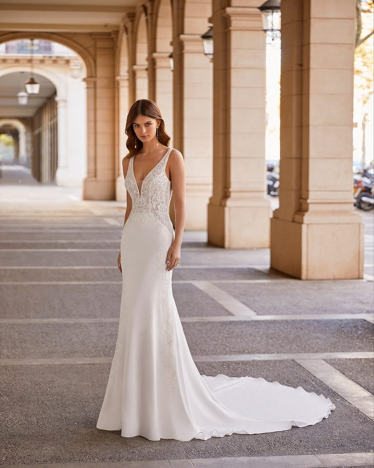 Romantic sheath-style wedding dress, made of stretch crepe, with a buttoned skirt throughout the train; with a deep-plunge neckline with beadwork detail, a plunging lace back, and double beadwork straps. Dreamy Luna Novias outfit made of stretch crepe combined with lace. LUNA_NOVIAS.