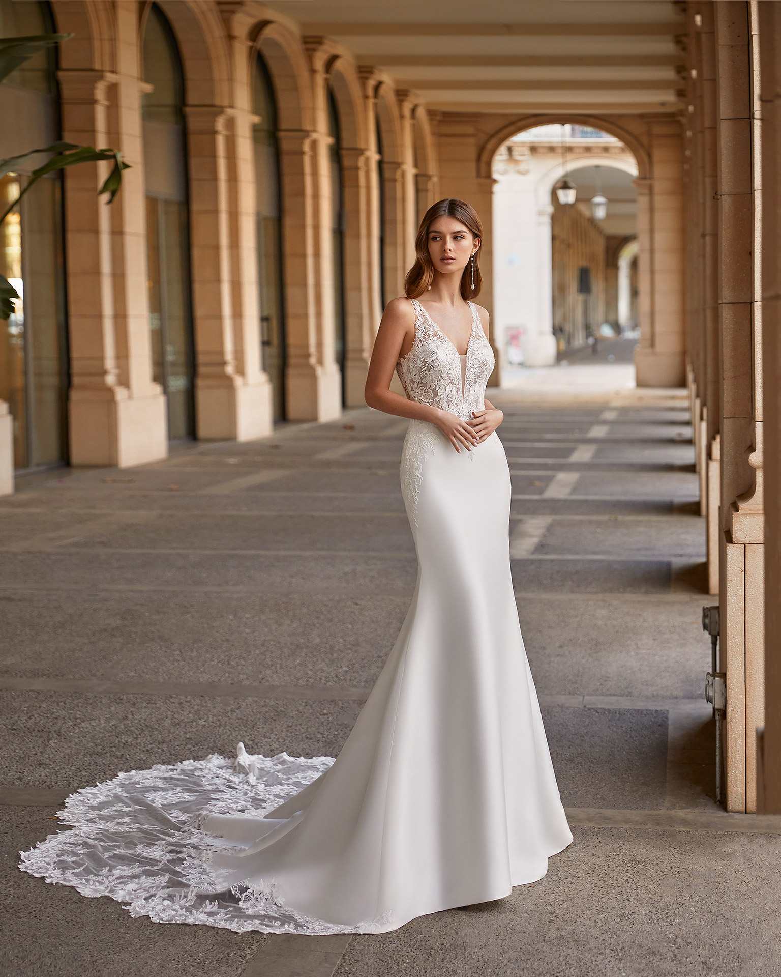 Romantic ballgown-style wedding dress, made of matt Mikado, with a sheath-style buttoned skirt throughout the train; with a deep-plunge neckline and a plunging lace back. Delicate Luna Novias outfit made of matt Mikado and lace. LUNA_NOVIAS.