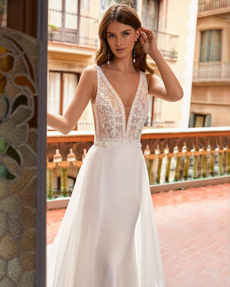 Two-piece sheath-style wedding dress made of stretch crepe, including an organza overskirt; with a deep-plunge neckline, sides and a V-back with lace with beadwork. Dreamy Luna Novias dress made of stretch crepe and lace. LUNA_NOVIAS.