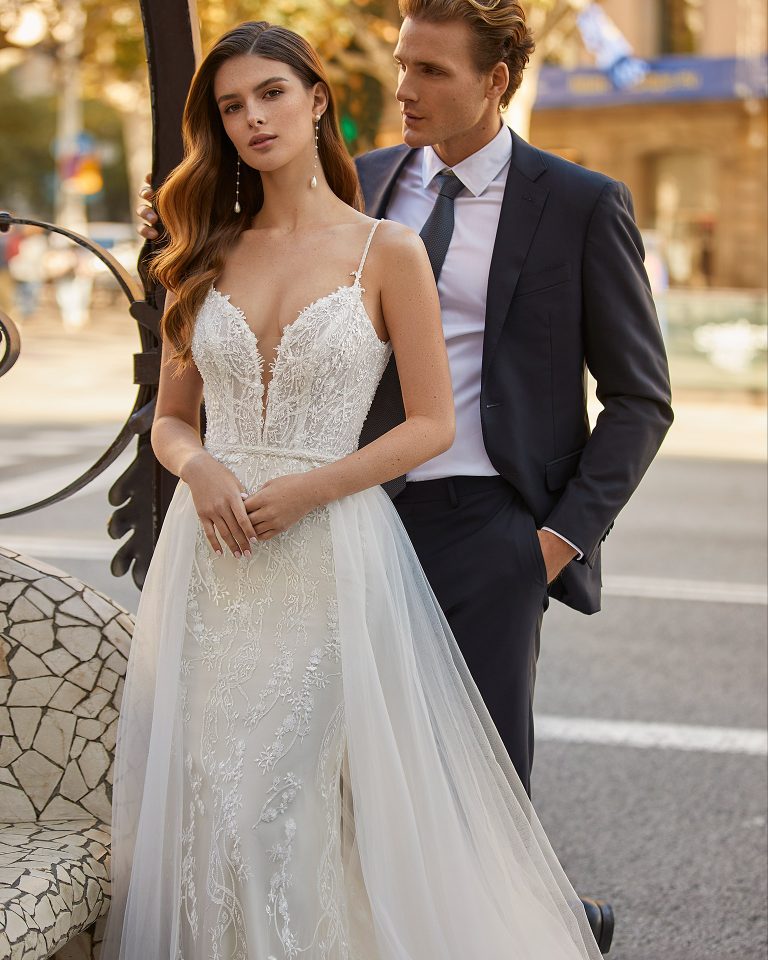 Two-piece mermaid-style wedding dress made of beadwork lace, including a tulle overskirt; with a deep-plunge neckline, an open lace and beadwork back, and straps with beadwork embroidered details. Exclusive Luna Novias outfit made of lace embellished with beadwork. LUNA_NOVIAS.