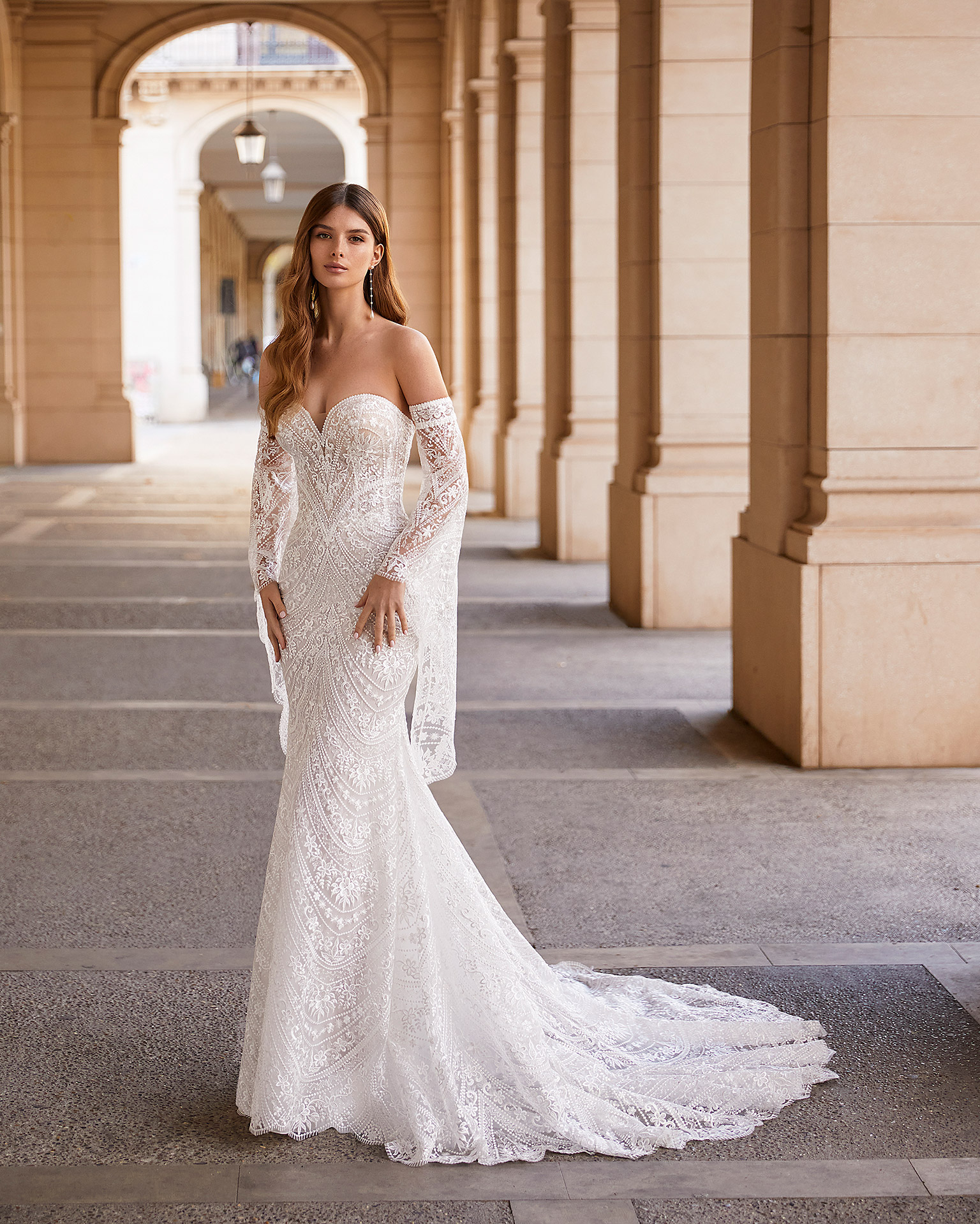 Romantic mermaid-style lace wedding dress, featuring flowing lace sleeves; with a push-up corset structure, a button-up back, and flowing sleeves. Exclusive Luna Novias outfit made of lace. LUNA_NOVIAS.