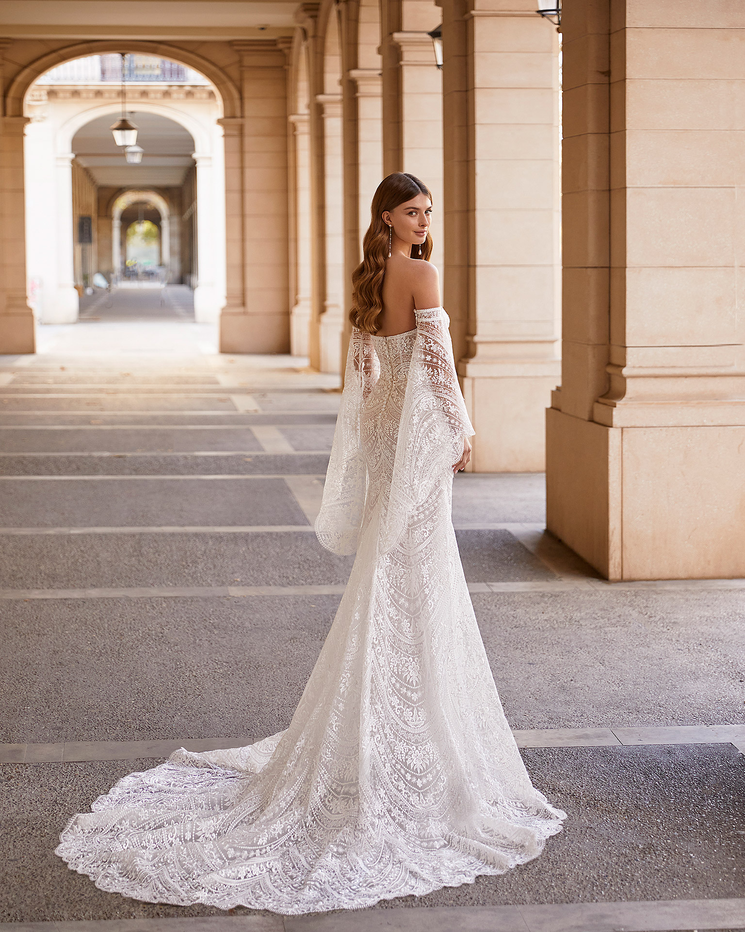 Romantic mermaid-style lace wedding dress, featuring flowing lace sleeves; with a push-up corset structure, a button-up back, and flowing sleeves. Exclusive Luna Novias outfit made of lace. LUNA_NOVIAS.
