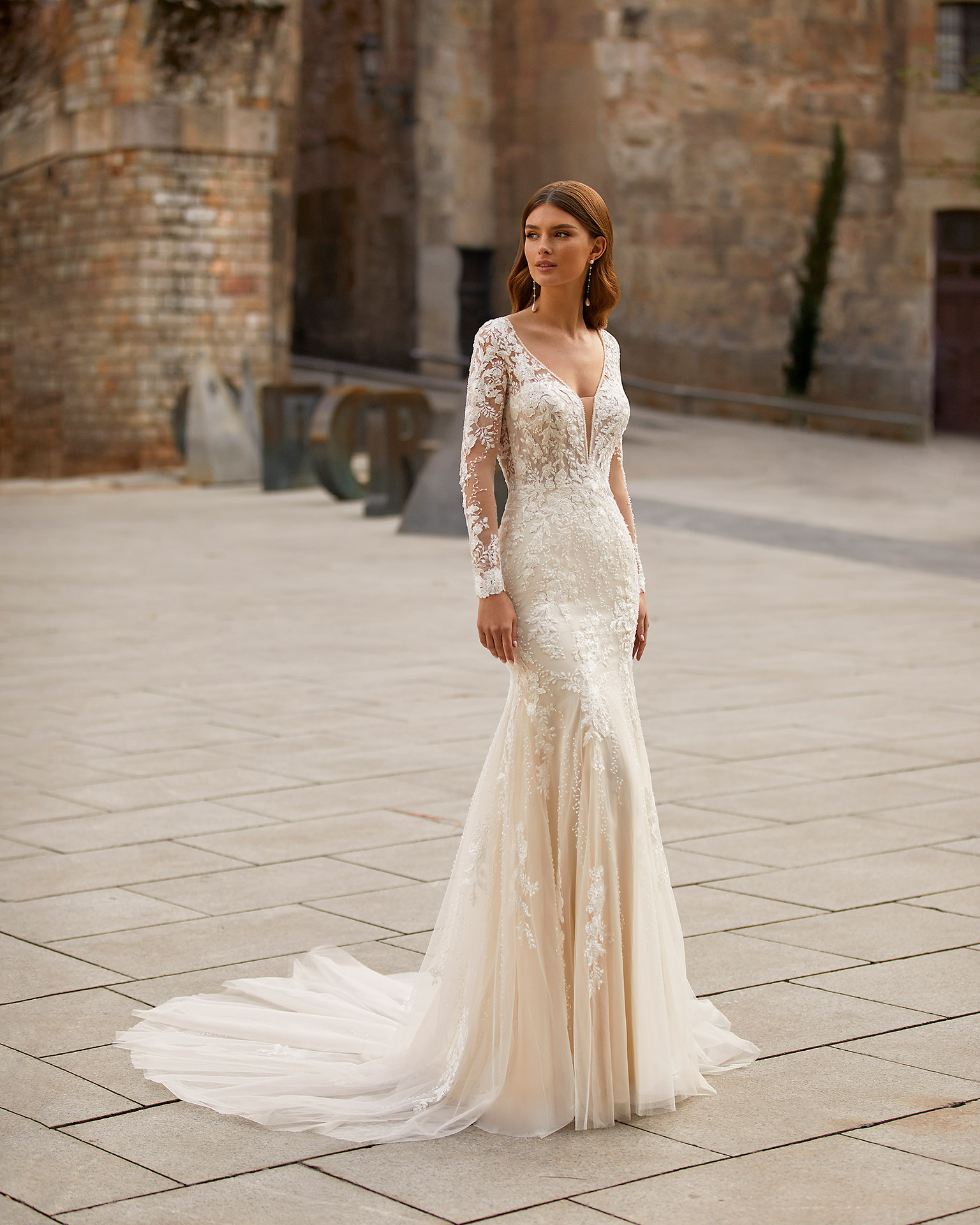 Sexy mermaid-style wedding dress, made of lace with a tulle skirt; with a deep-plunge neckline with beadwork detail, a back with a round slit, and long tulle and lace sleeves. Unique Luna Novias look made of lace embellished with beadwork. LUNA_NOVIAS.