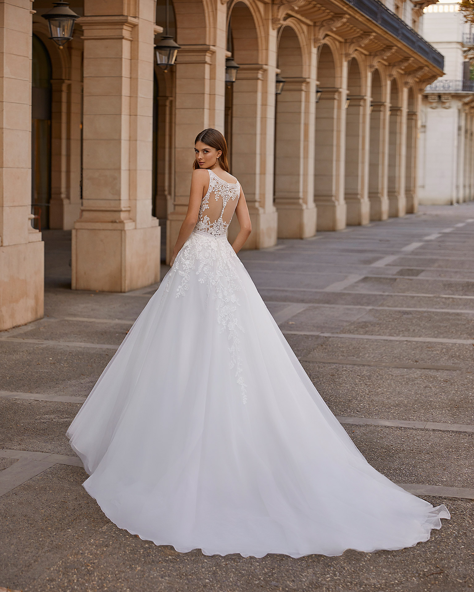 Princess-style A-line wedding dress, made of tulle with lace appliqués; with a deep-plunge neckline, and a button-up back with sheer inserts. Exclusive Luna Novias dress made of tulle with beadwork and lace appliqués. LUNA_NOVIAS.