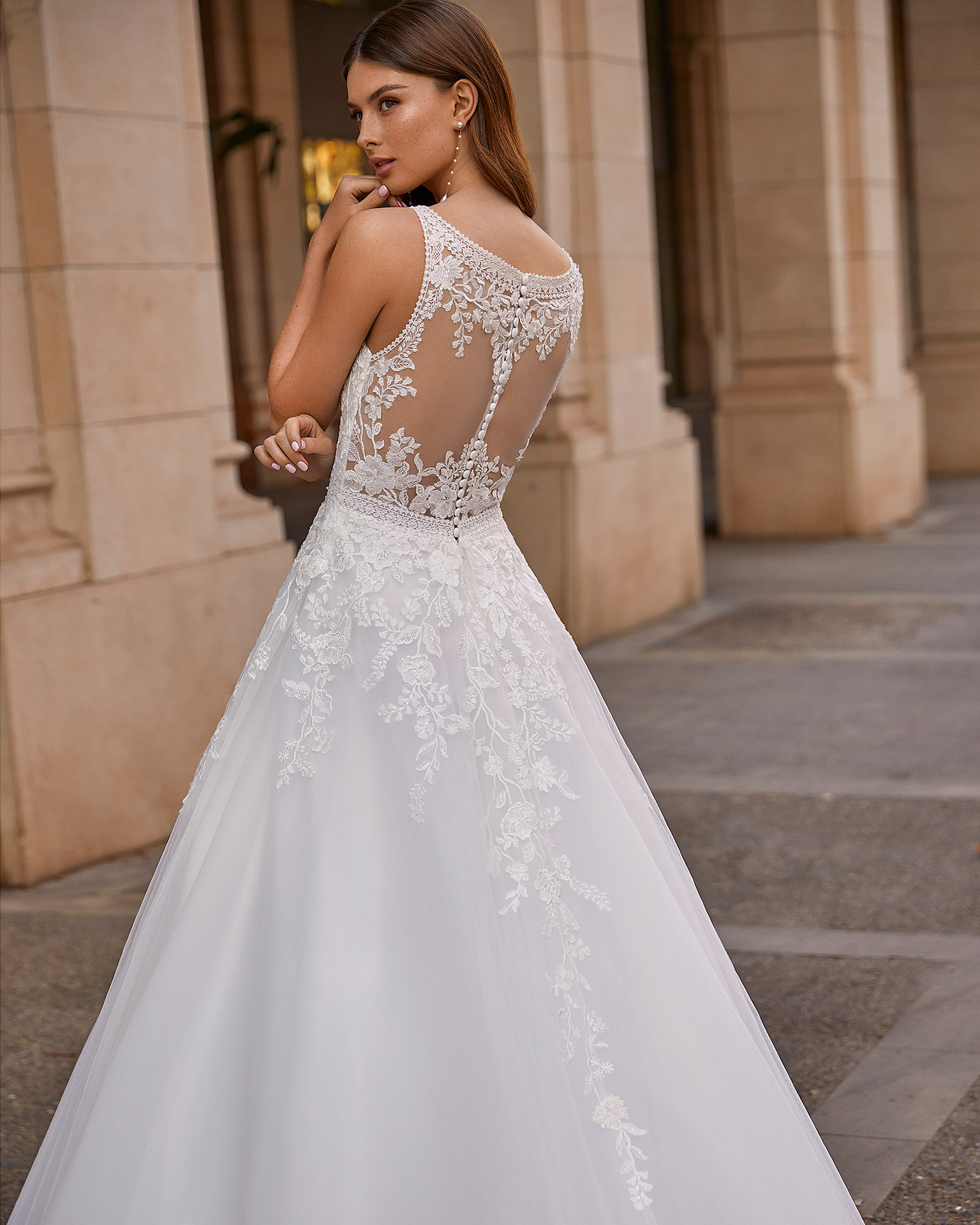 Princess-style A-line wedding dress, made of tulle with lace appliqués; with a deep-plunge neckline, and a button-up back with sheer inserts. Exclusive Luna Novias dress made of tulle with beadwork and lace appliqués. LUNA_NOVIAS.