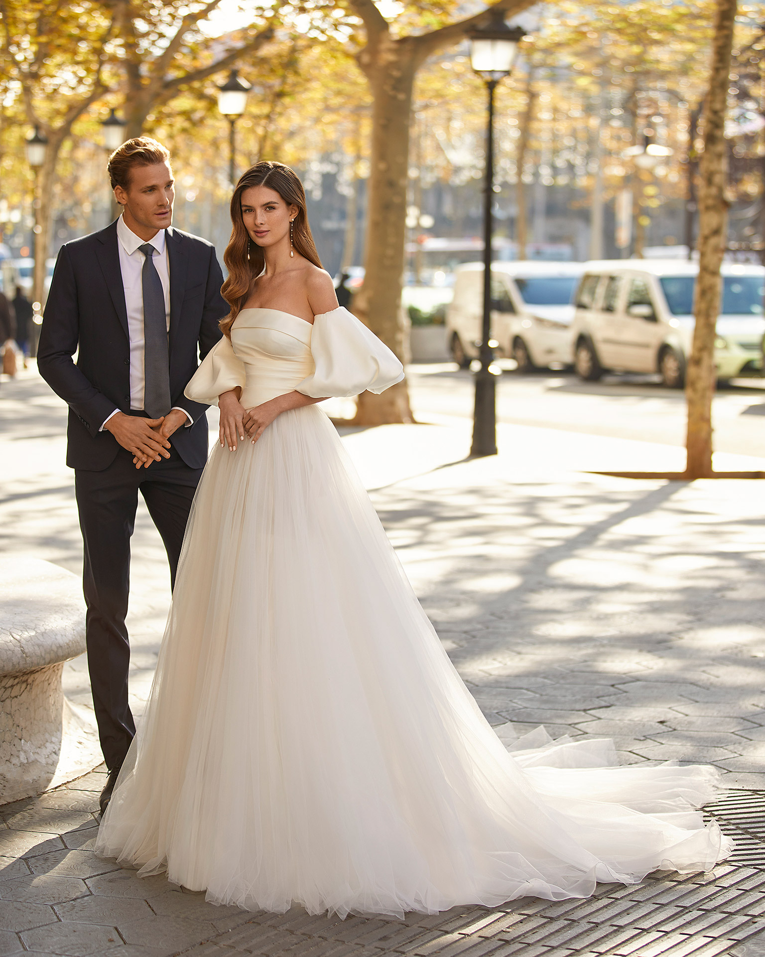 Modern princess-style wedding dress, made of tulle, featuring a matt Mikado pleated bodice; with a strapless neckline, a button-up back, and puffed sleeves. Trendy Luna Novias design made of tulle combined with matt Mikado. LUNA_NOVIAS.