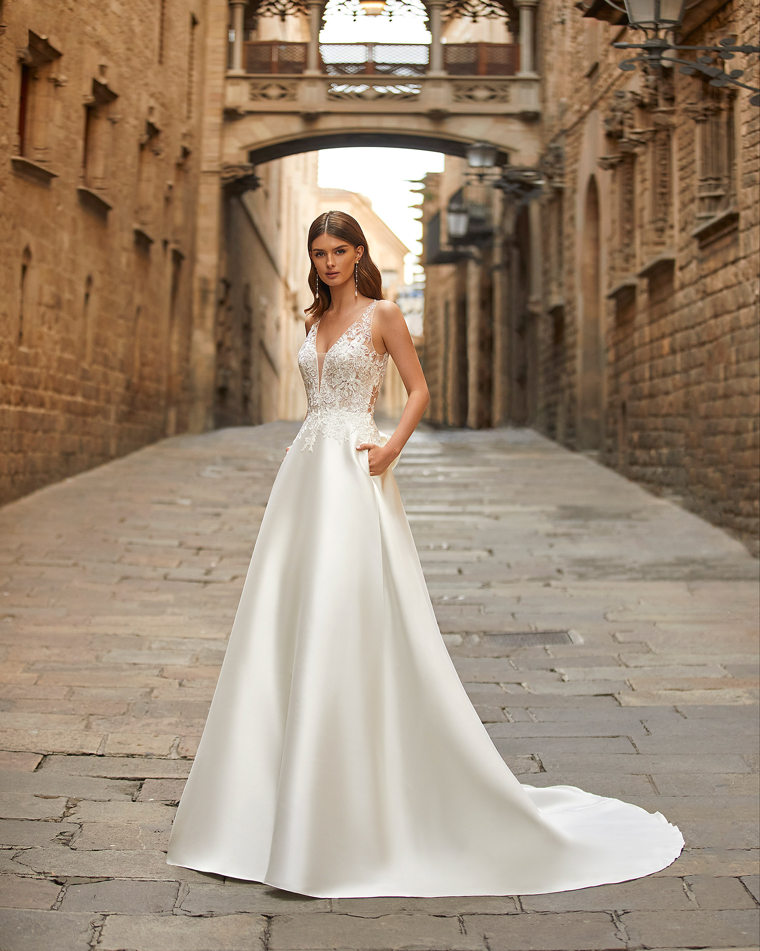 Elegant A-line wedding dress, made of matt Mikado, with a sheath-style skirt with pockets; with a deep-plunge neckline with delicate beadwork detail, and an illusion lace button-up back. Delicate Luna Novias look made of matt Mikado combined with lace. LUNA_NOVIAS.