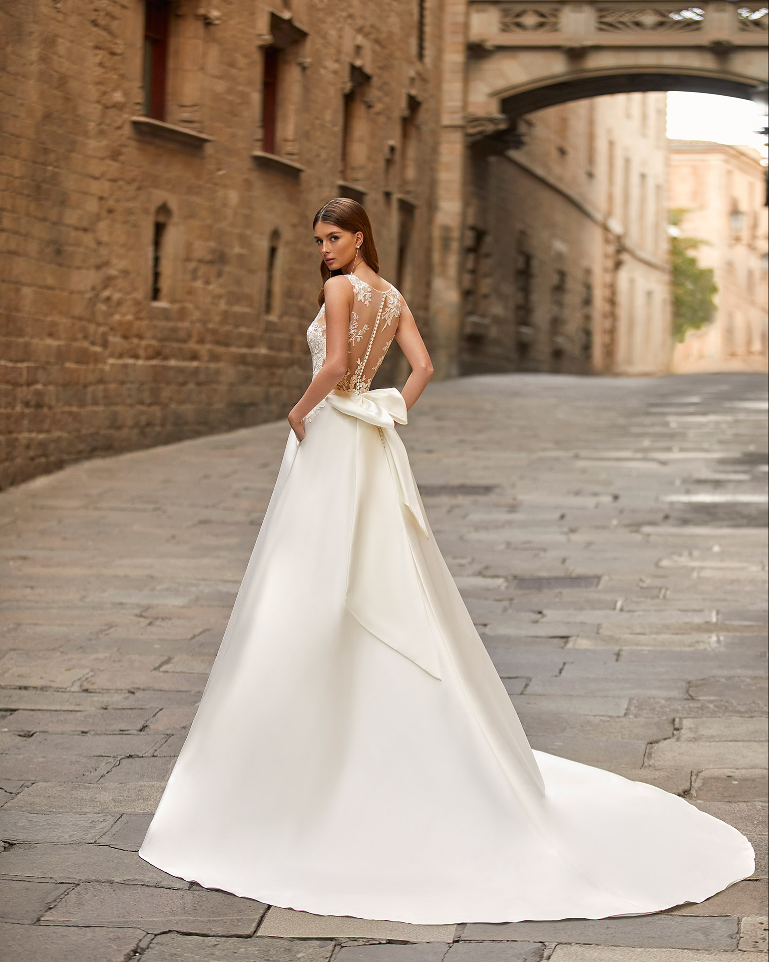 Elegant A-line wedding dress, made of matt Mikado, with a sheath-style skirt with pockets; with a deep-plunge neckline with delicate beadwork detail, and an illusion lace button-up back. Delicate Luna Novias look made of matt Mikado combined with lace. LUNA_NOVIAS.