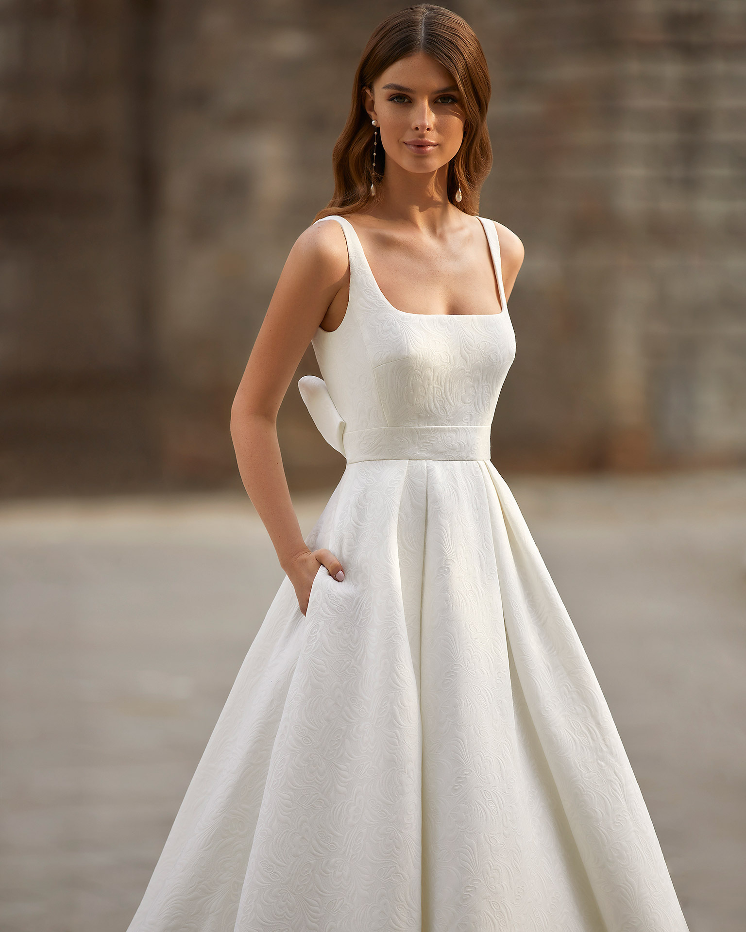 Classic-style wedding dress, made of Veneto brocade, with a voluminous sheath-style skirt; with a square neckline, an open back, and a bow at the back. Unique Luna Novias design made entirely of Veneto brocade. LUNA_NOVIAS.