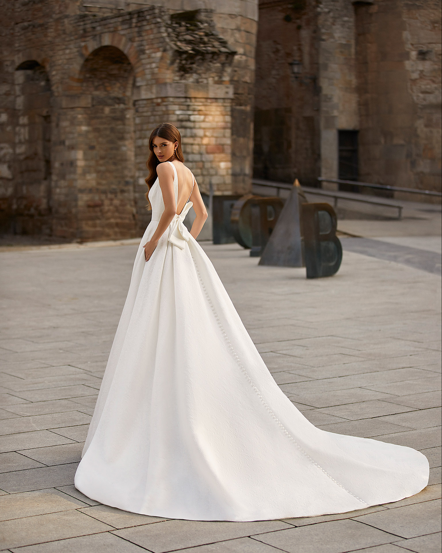 Classic-style wedding dress, made of Veneto brocade, with a voluminous sheath-style skirt; with a square neckline, an open back, and a bow at the back. Unique Luna Novias design made entirely of Veneto brocade. LUNA_NOVIAS.