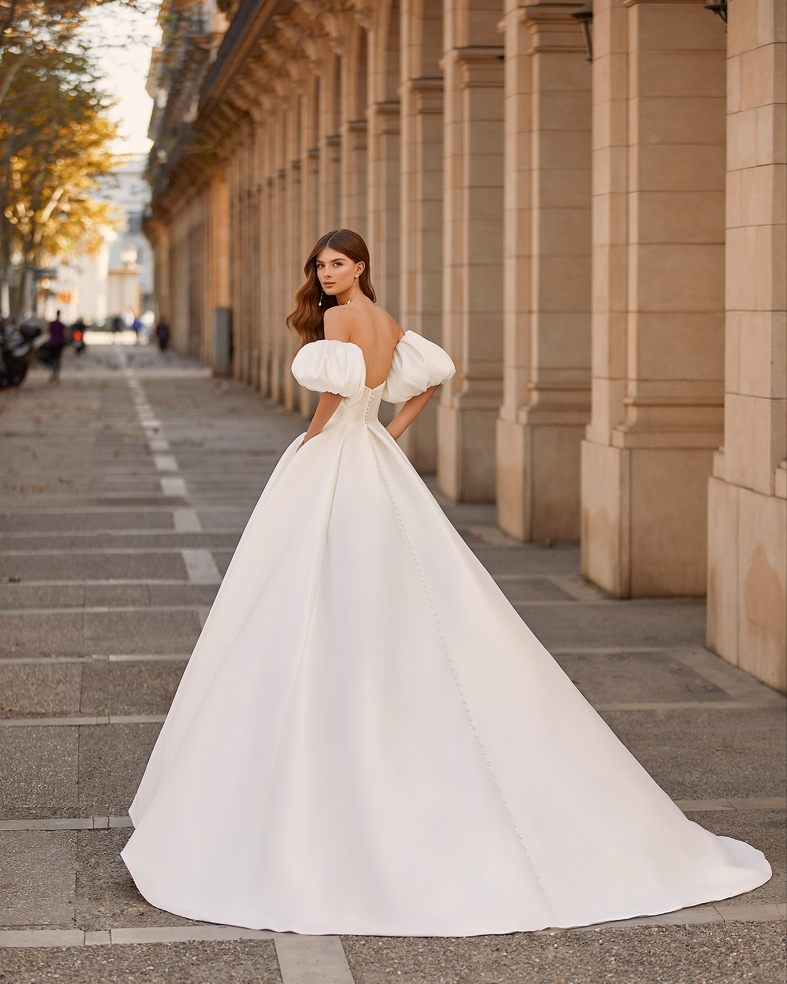 Classic princess-style wedding dress, made of matt Mikado, with a voluminous sheath-style skirt; with a strapless neckline, a buttoned back down to the end of the train, and puffed sleeves. Dreamy Luna Novias dress made entirely of Mikado. LUNA_NOVIAS.