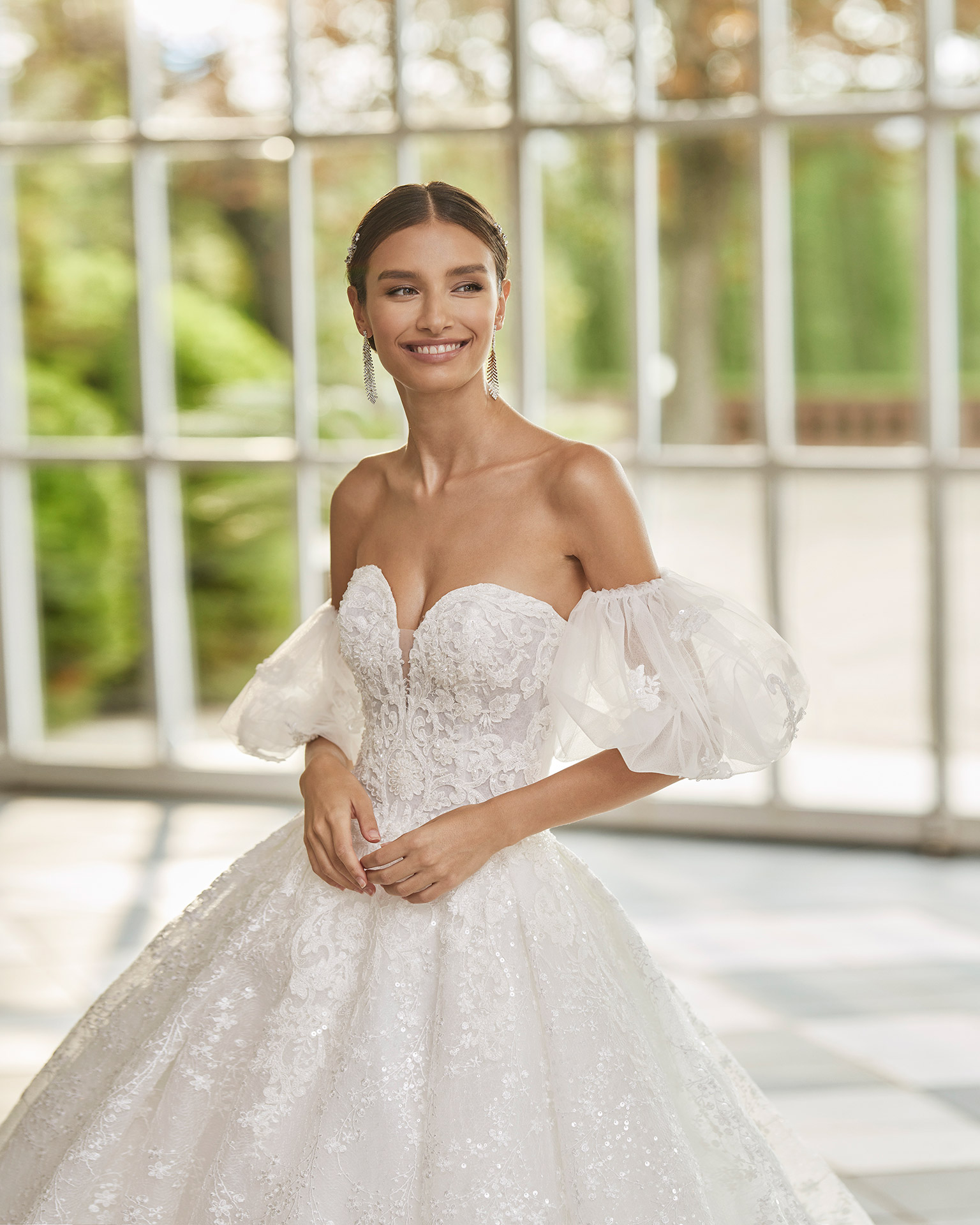 Romantic princess-style wedding dress, with a full sheath-style skirt; with a sweetheart neckline, a corset back, and puffed tulle sleeves. Dreamy Luna Studio dress made of tulle and lace, with beadwork finishes. LUNA_NOVIAS.
