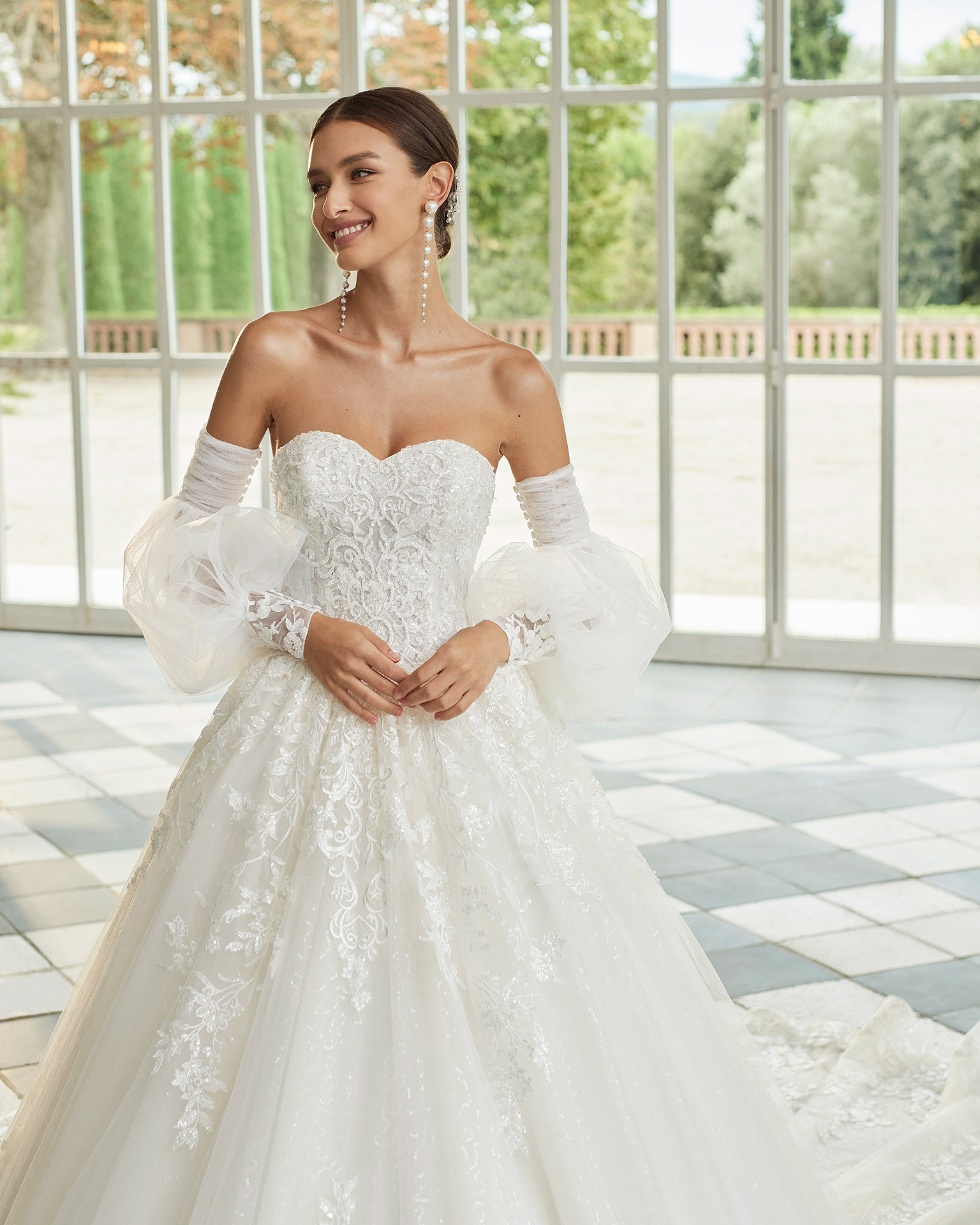 Two-piece princess-style wedding dress, featuring a full skirt; with a sweetheart neckline, a corset back, and long puffed tulle sleeves with lace and beadwork cuffs. Dreamy Luna Studio outfit made of tulle and beadwork embroidered lace. LUNA_NOVIAS.