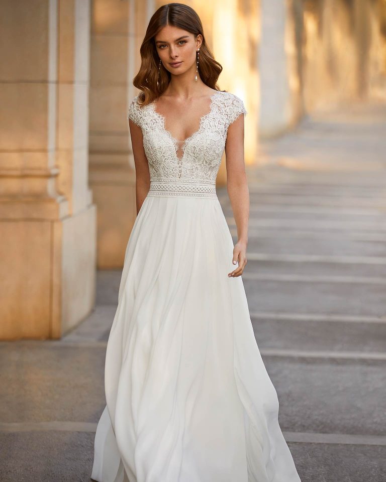 Flowing ballgown-style wedding dress made of Georgette, with a lace bodice; with a deep-plunge neckline, a lace and beadwork V-back, and short lace sleeves. Exclusive Luna Novias design made of Georgette and beadwork lace. LUNA_NOVIAS.
