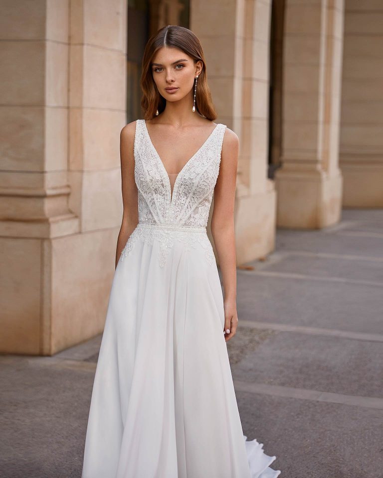 Flowing ballgown-style wedding dress, made of Georgette, with a lace bodice and beadwork detail on the necklines; with a deep-plunge neckline, with sides and a V-back in lace with beadwork. Unique Luna Novias look made of Georgette combined with beadwork lace. LUNA_NOVIAS.