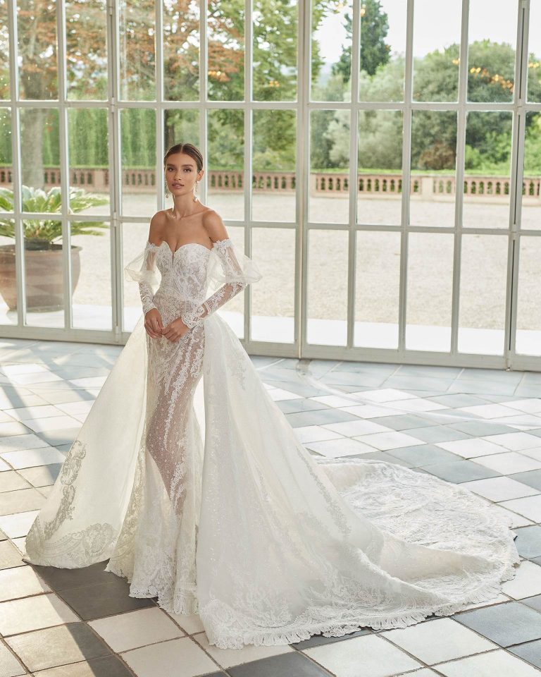 Two-piece mermaid-style wedding dress, with a voluminous overskirt; with a sweetheart neckline, a corset back, and long puffed sleeves. Unique Luna Studio outfit made of tulle and lace embellished with beadwork. LUNA_NOVIAS.