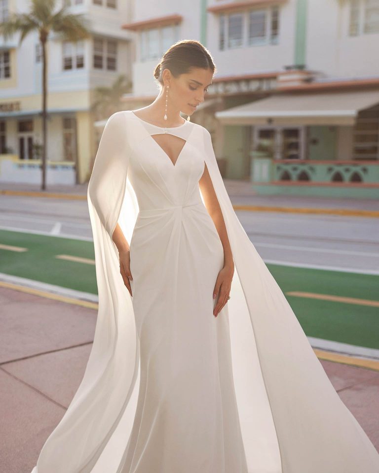 Simple A-line wedding dress, crafted in georgette. This delicate Luna Novias design features a V-neckline, V-back, straps, and a crepe cape. LUNA_NOVIAS.